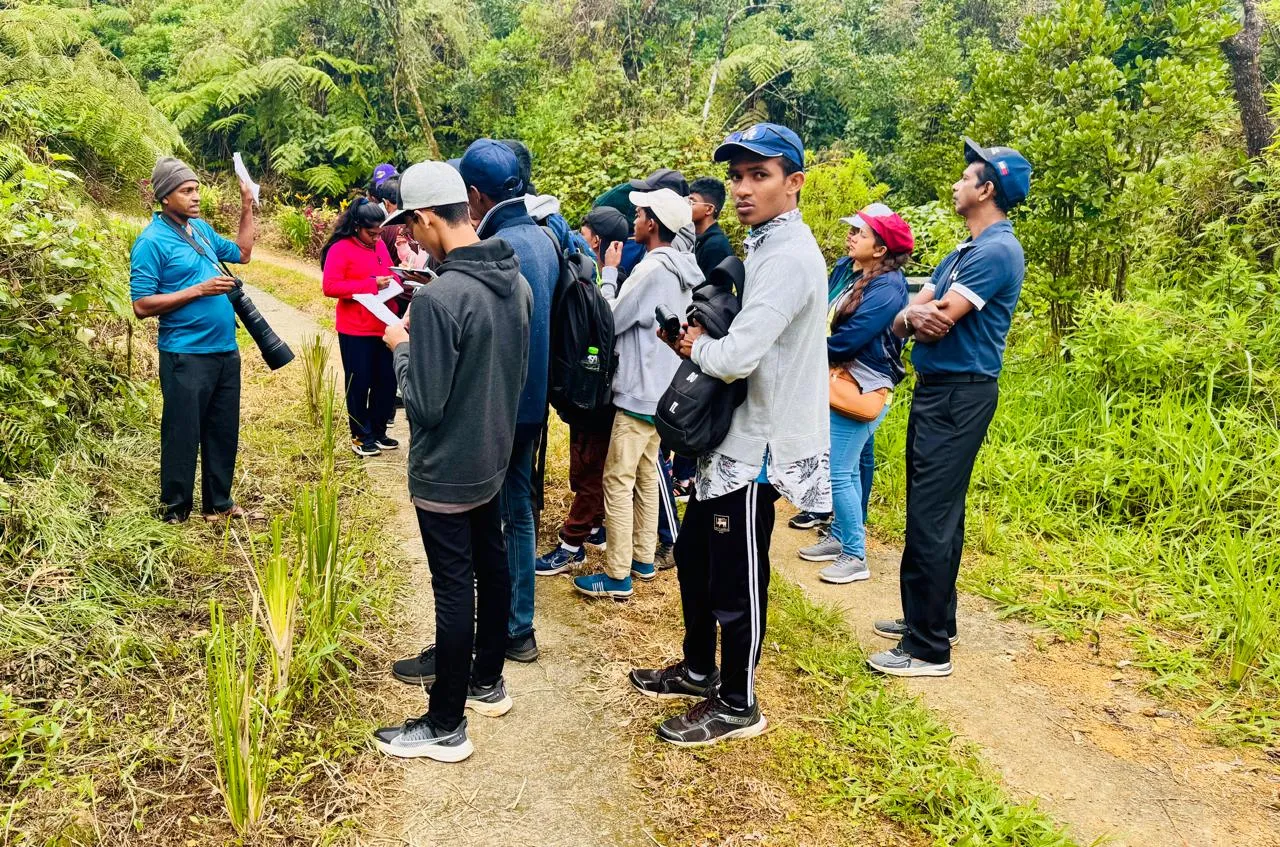Students taking notes during a daytime field study session on a forest trail.