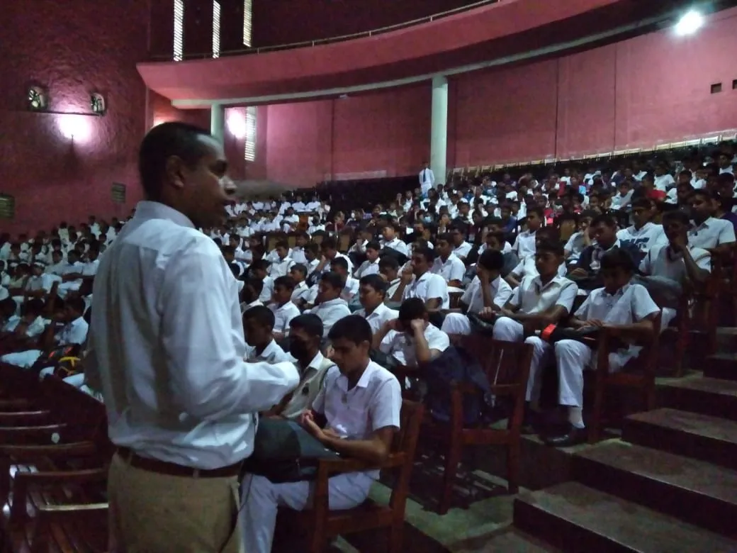 Nayana Pradeep speaking among students seated in the Dharmaraja College auditorium.