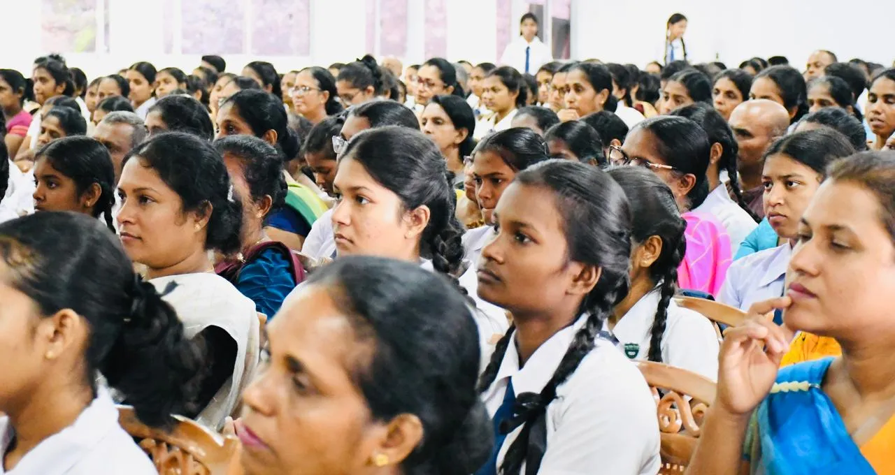 A/L students in school uniform seated beside their parents, listening attentively.