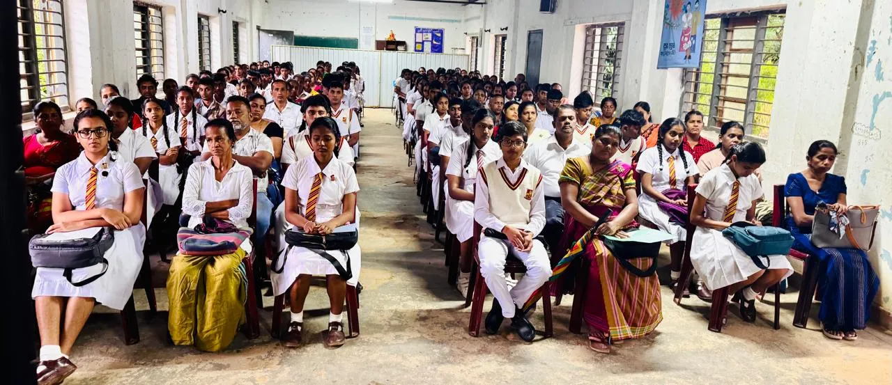 Rows of Advanced Level students in school uniform seated with their parents in the hall.