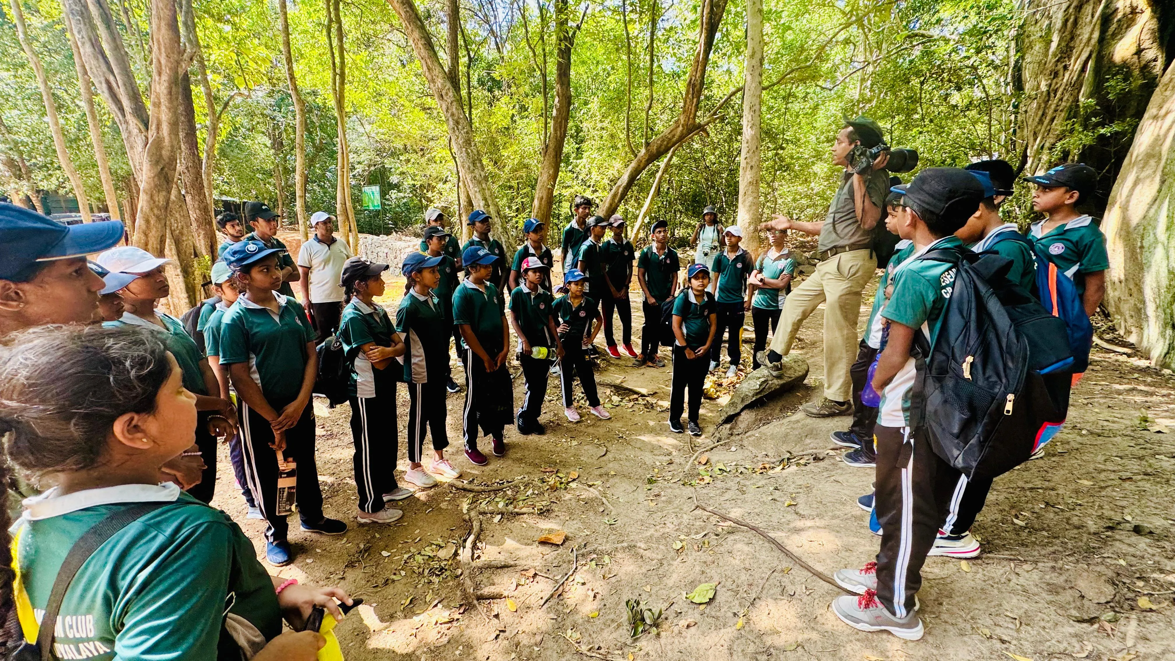 Nayana Pradeep addressing a circle of students in the forest.