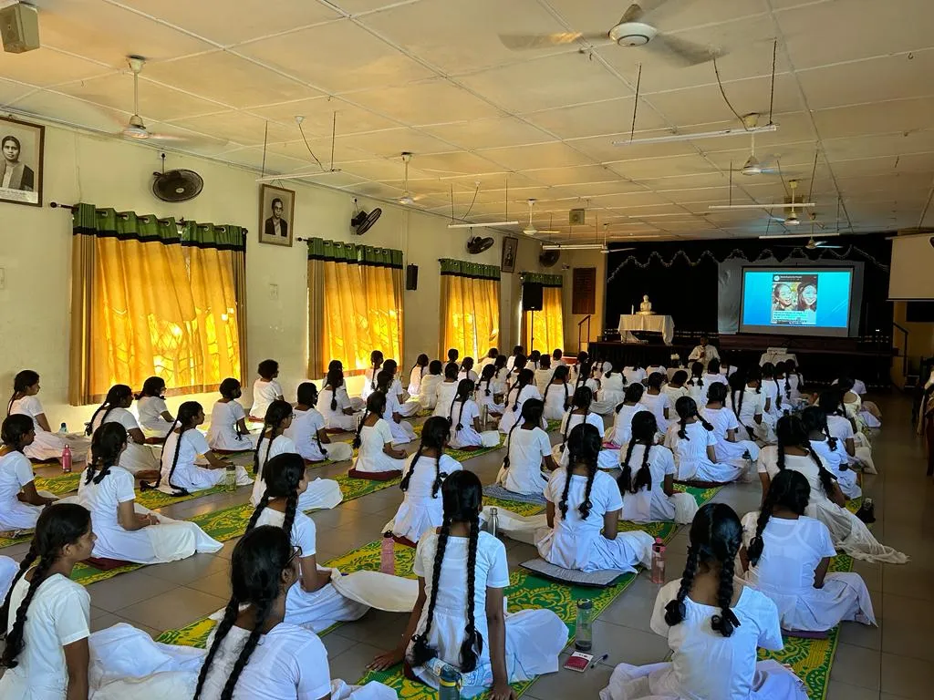 A wide view of students practising seated mindfulness together in the school hall.