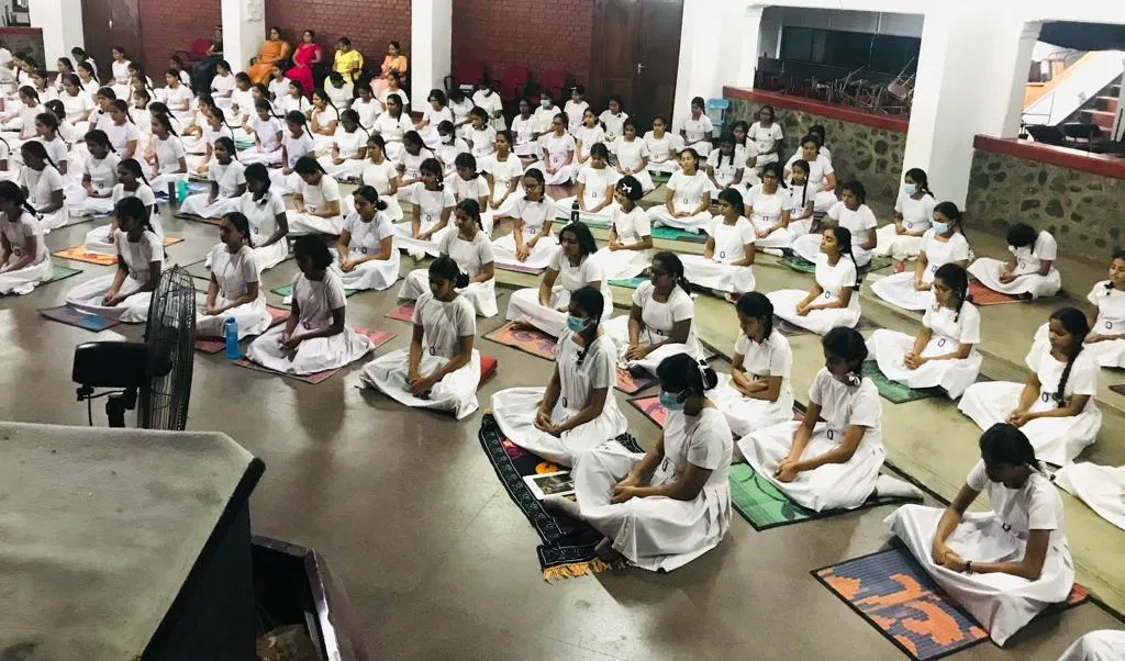 Students practising mindfulness together while seated in orderly rows.