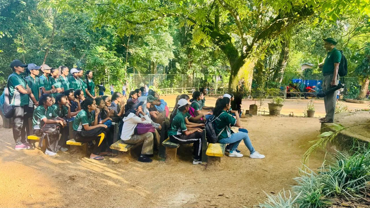 Nayana Pradeep addressing students seated under a large tree.
