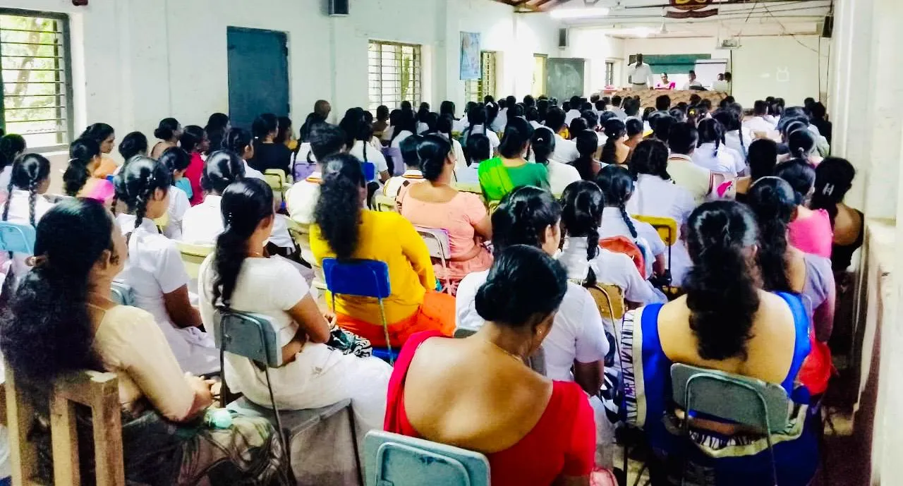 A packed hall seen from the back, with students and parents facing the front during the session.