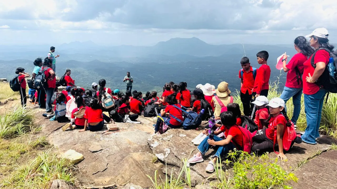 Students seated on the summit rock overlooking the valley below.