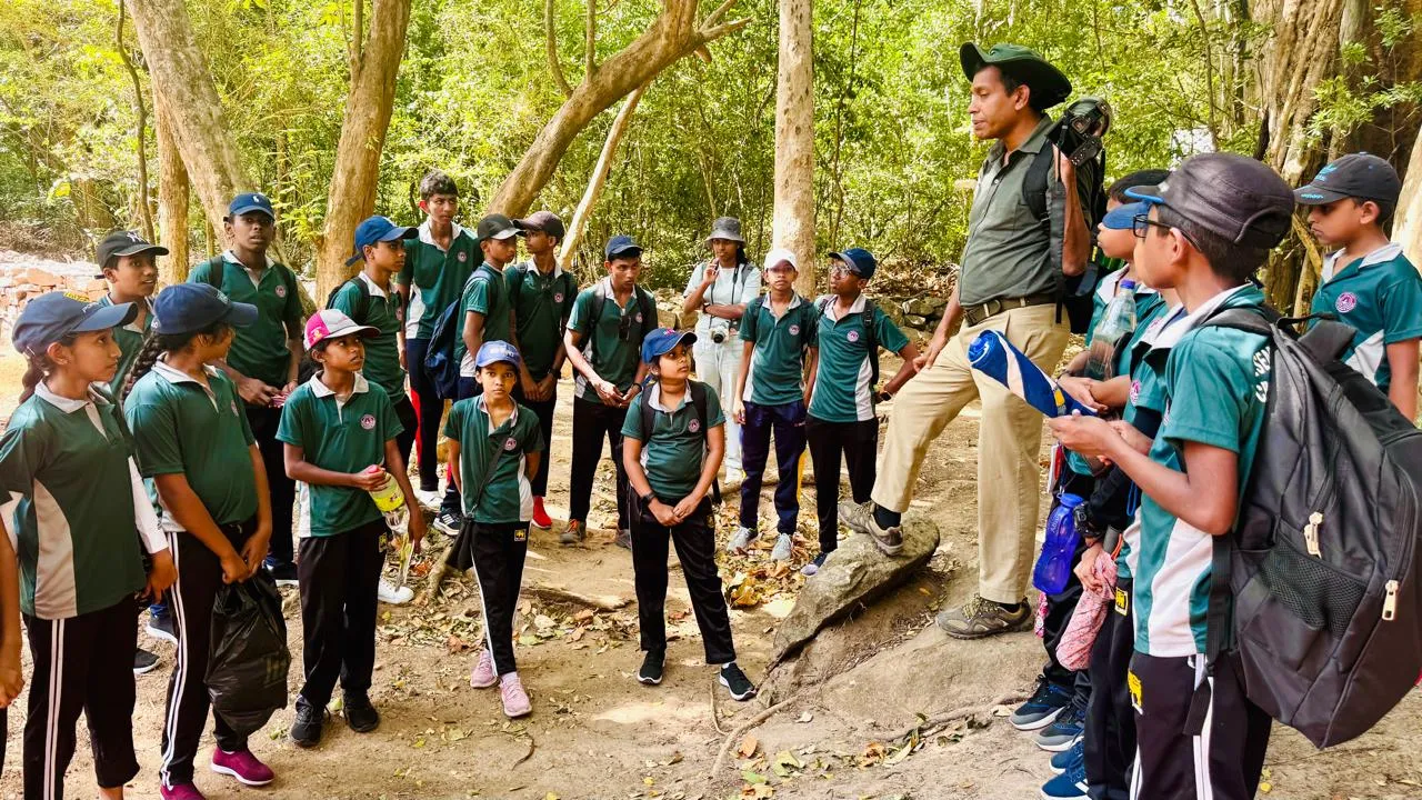 Nayana Pradeep explaining to students gathered around a rock on the trail.