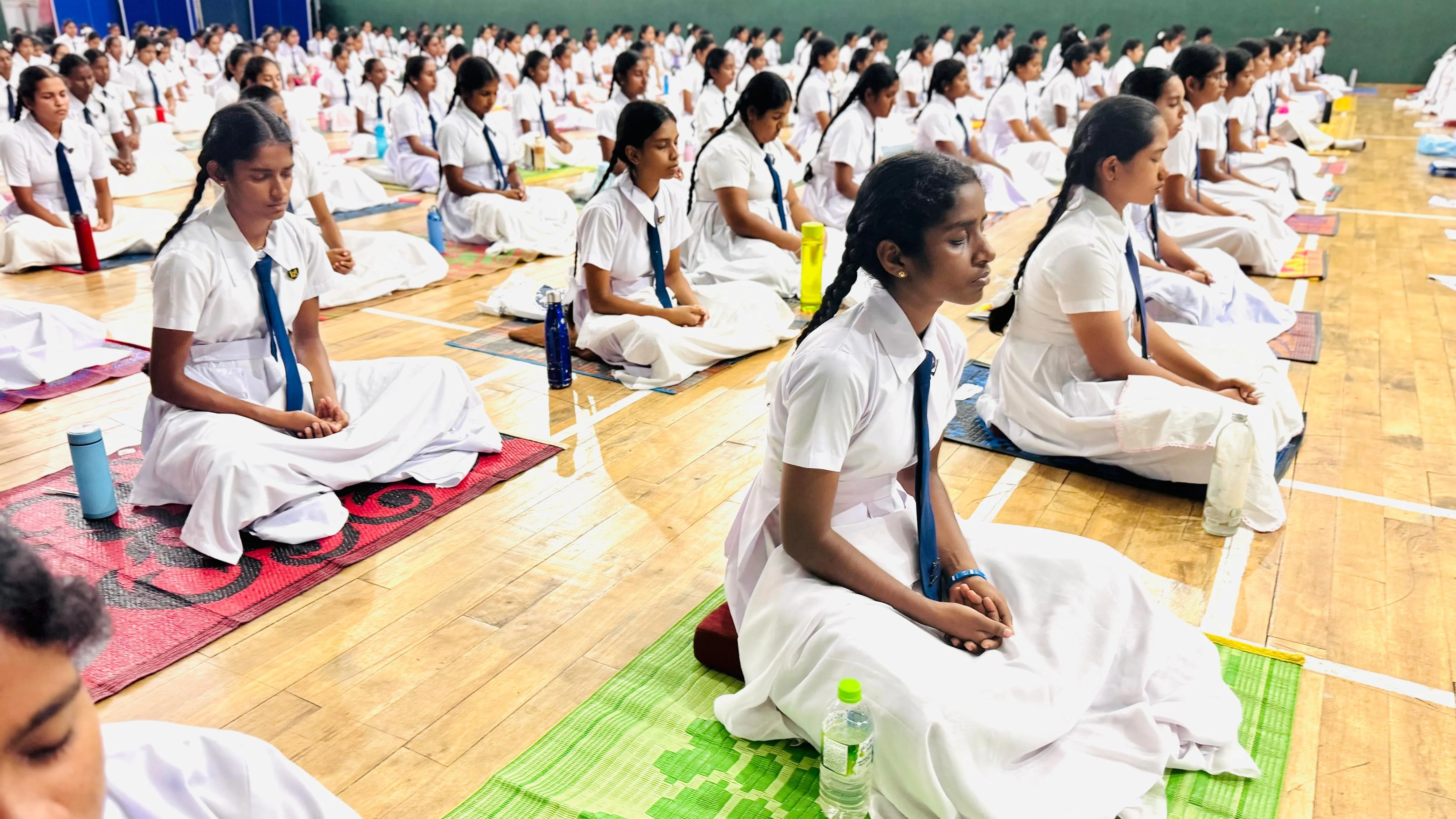 A closer view of students meditating on mats in the hall.
