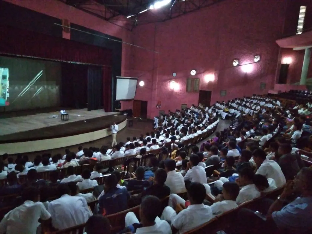 Nayana Pradeep presenting to a large audience of G.C.E. Advanced Level students in the Dharmaraja College auditorium.