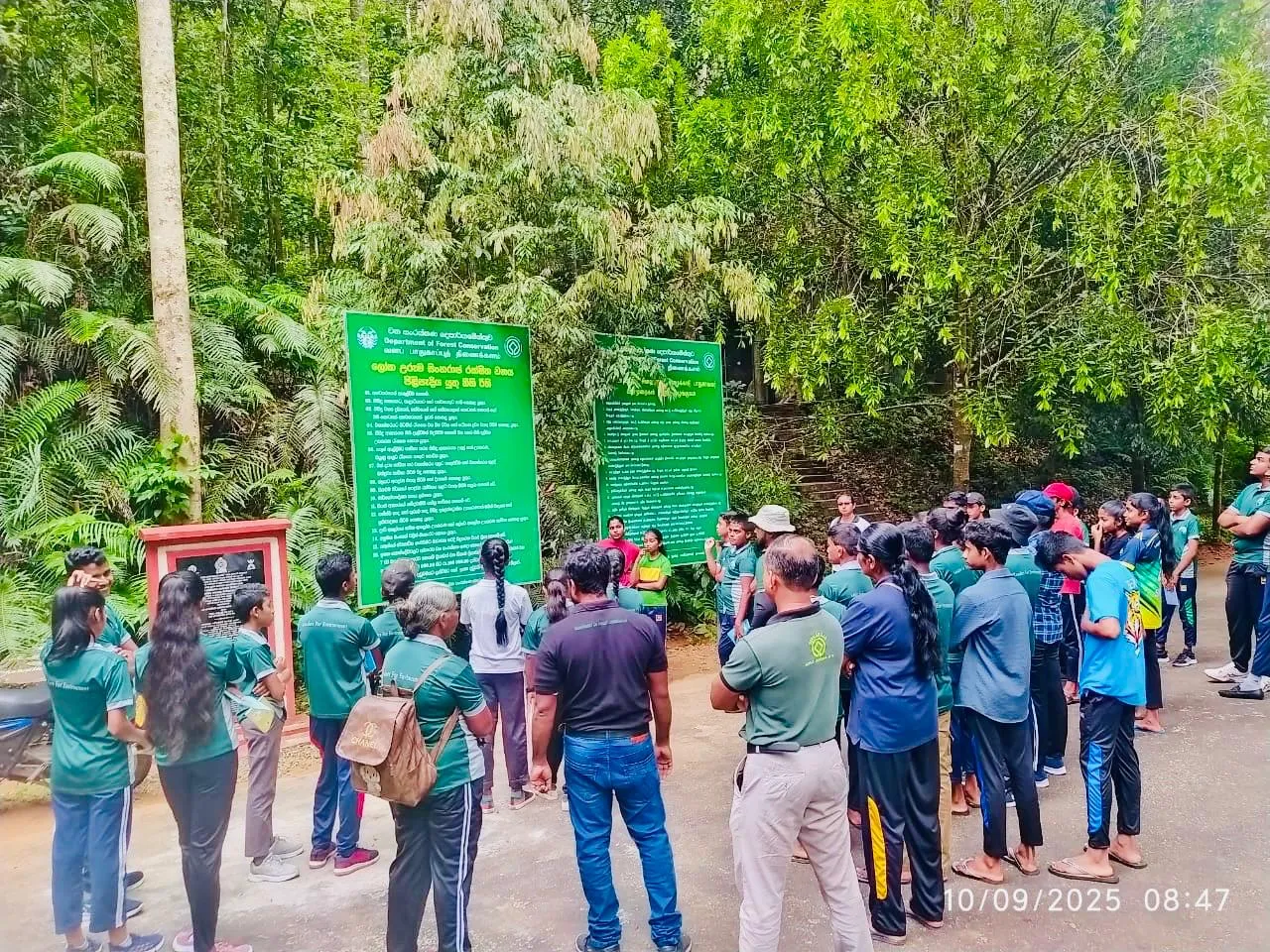 Students gathered at the Sinharaja Forest Reserve entrance signboards for the environmental workshop.