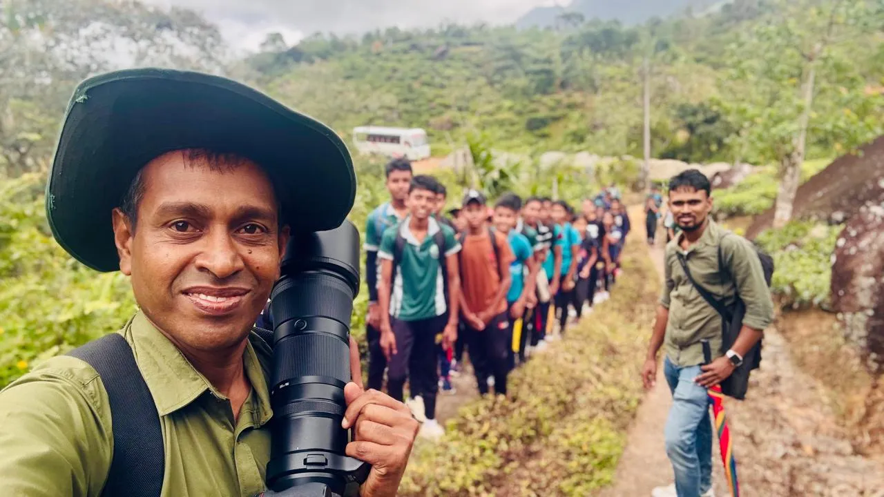 Nayana Pradeep with his camera leading a line of Pothupitiya Maha Vidyalaya students along a trail toward Sinharaja.