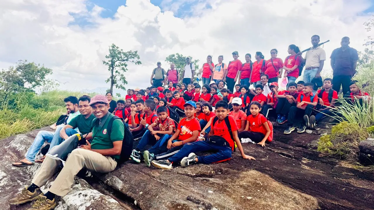Group photograph of Ambagamuwa Model Primary School students on the rocky summit at Bathalegala, with Nayana Pradeep at the front.