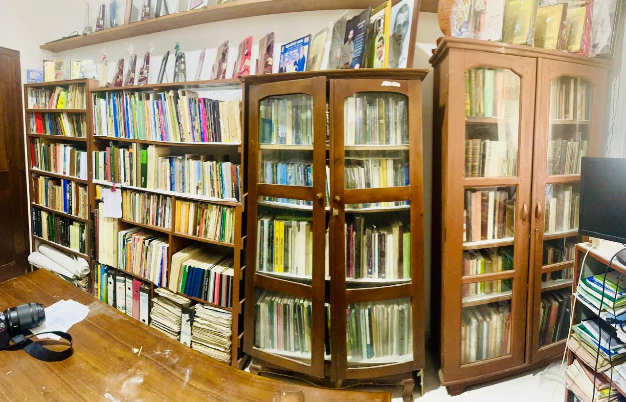 Open shelves and glass-fronted cabinets holding hundreds of volumes, with awards displayed on top.