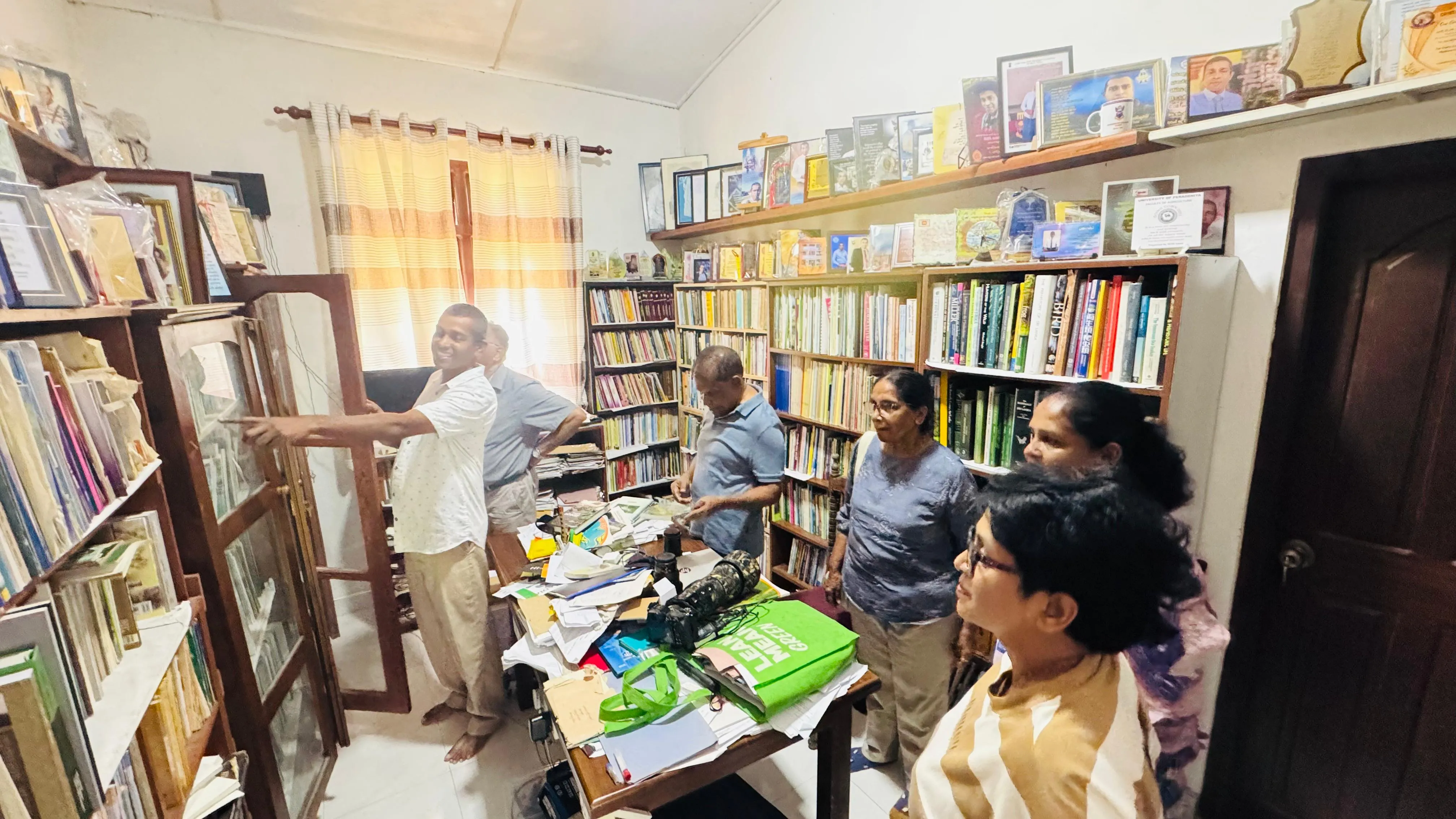 Adult visitors and researchers browsing the library’s glass-fronted cabinets and shelves during a visit.
